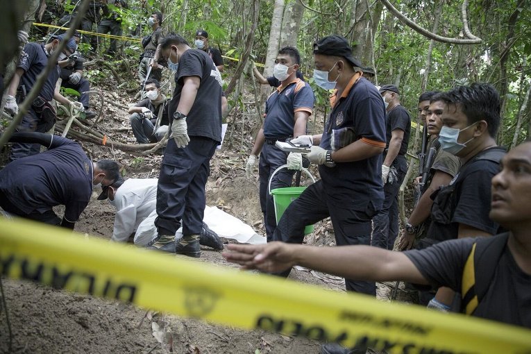Судебно-медицинские эксперты обследуют место массовых захоронений в Северной Малайзии на границе с Таиландом