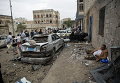 Человек отдыхает рядом с его автомобилем, поврежденным авиаударами в Сане, Йемен