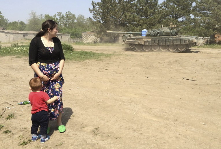 Женщина с мальчиком смотрит на танк в поселке Хутор Чкалова возле российско-украинской границы в Ростовской области