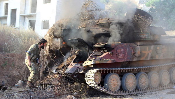 Член Аль-Каиды у горящего танка на северо-западе города Ариха в Сирии