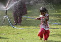 Индийский ребенок играет с водой, чтобы остыть в жаркий летний день в Хайдарабаде, Индия