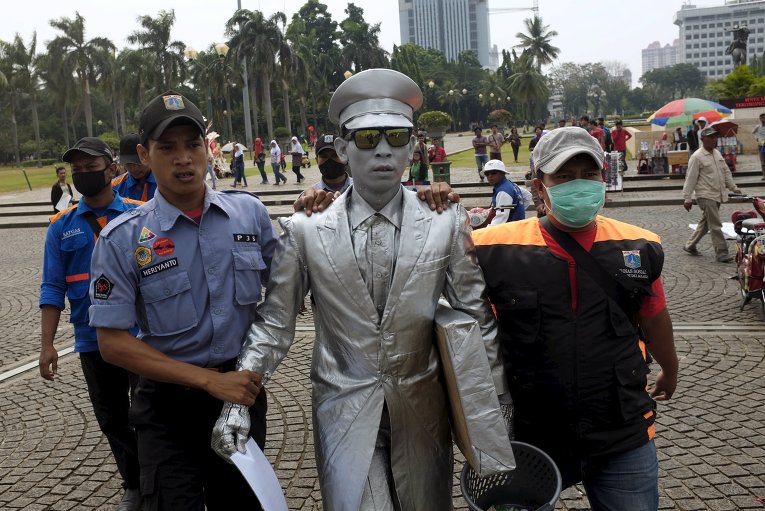 Сотрудники правоохранительных органов забирают уличного музыканта в Джакарте, Индонезия