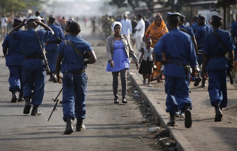 Женщина проходит мимо полицейских во время акции протеста против президента Бурунди Пьера Нкурунзиза и его заявке на третий срок.