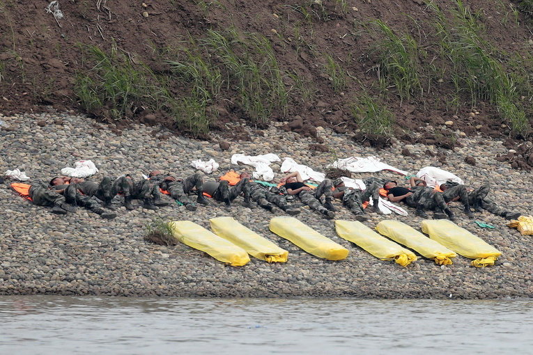 Спасатели отдыхают рядом с местом, где перевернулась круизное судно Восточная звезда в провинции Хубэй Китая