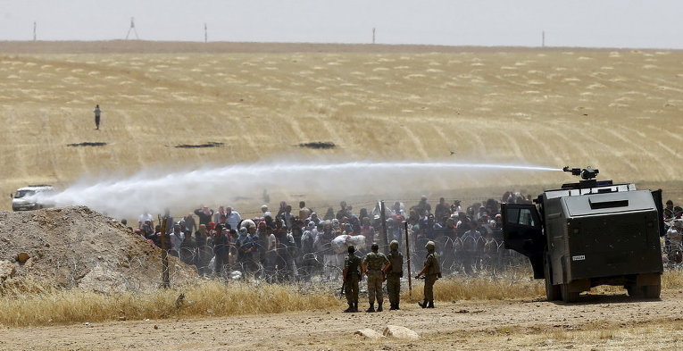 Турецкие военные используют водометы, чтобы остановить сирийских беженцев, которые хотят проникнуть в Турцию