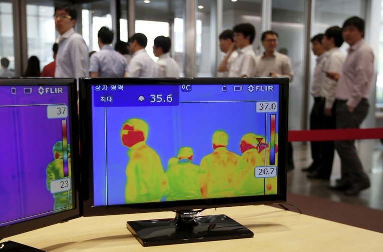 Сотрудники одного из предприятий Южной Кореи заходят в офис мимо тепловизионных камер