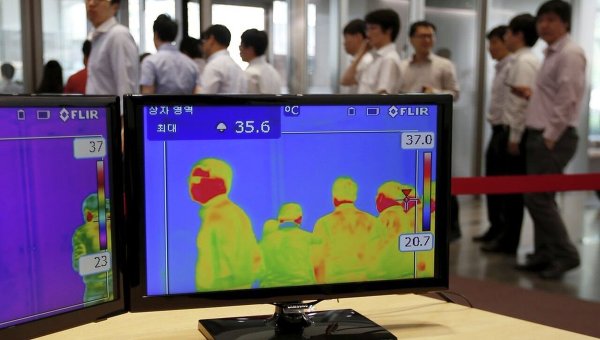 Сотрудники одного из предприятий Южной Кореи заходят в офис мимо тепловизионных камер