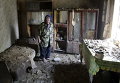 Пожилая женщина осматривает развалины дома, разрушенного обстрелами на окраине Донецка