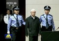 Полицейские ведут Чжоу Юнкана, бывшего члена Коммунистической партии Постоянного комитета Политбюро, отвечающего за безопасность, в зал суда в Тяньцзине, Китай