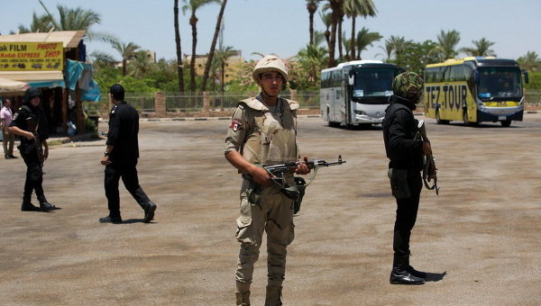 Египетские силы безопасности стоят на страже перед туристических автобусов на месте теракта возле Карнакского храма в Луксоре, Египет