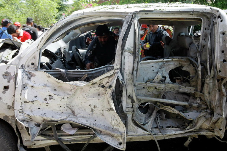 Пакистанские полицейские осматривают автомобиль, взорванный во время теракта в Пешаваре, Пакистан