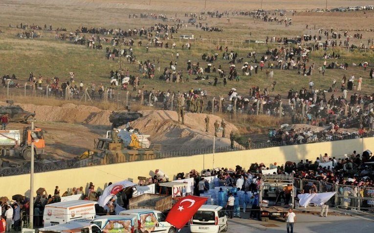 Беженцы из города Тель-Абьяд на севере Сирии выстраиваются у границы Турции, чтобы попасть в провинцию Шанлыурфа