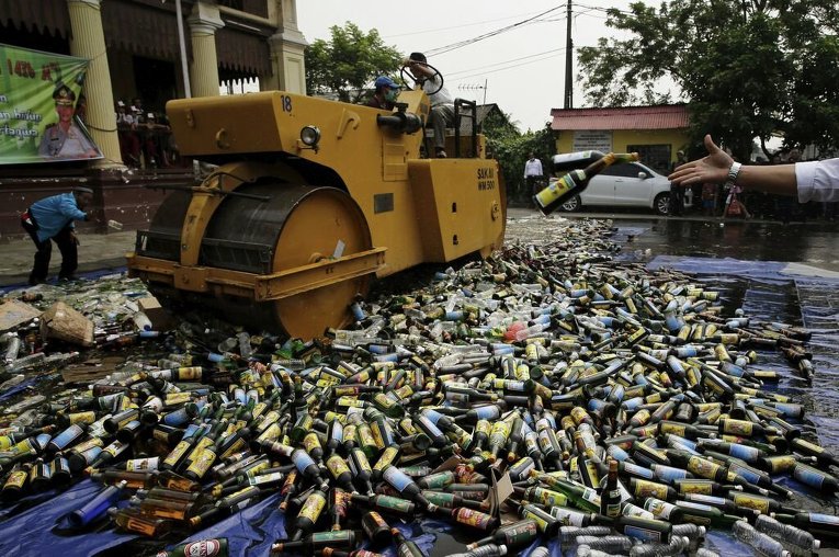 Полицейский бросает бутылки алкогольных напитков для уничтожения возле отделения полиции Западной Джакарты