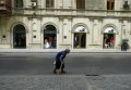 Женщина подметает улицу, где размещены модные бутики в Баку