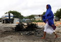 Сомалийская женщина проходит мимо места взрыва автомобиля в столице Могадишо