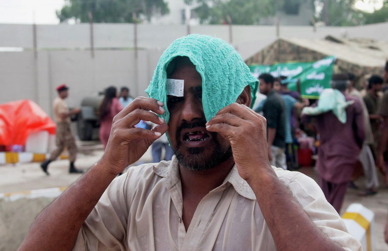 Мужчина накрывает голову мокрым полотенцем, чтобы избежать теплового удара в Карачи, Пакистан