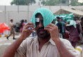 Мужчина накрывает голову мокрым полотенцем, чтобы избежать теплового удара в Карачи, Пакистан