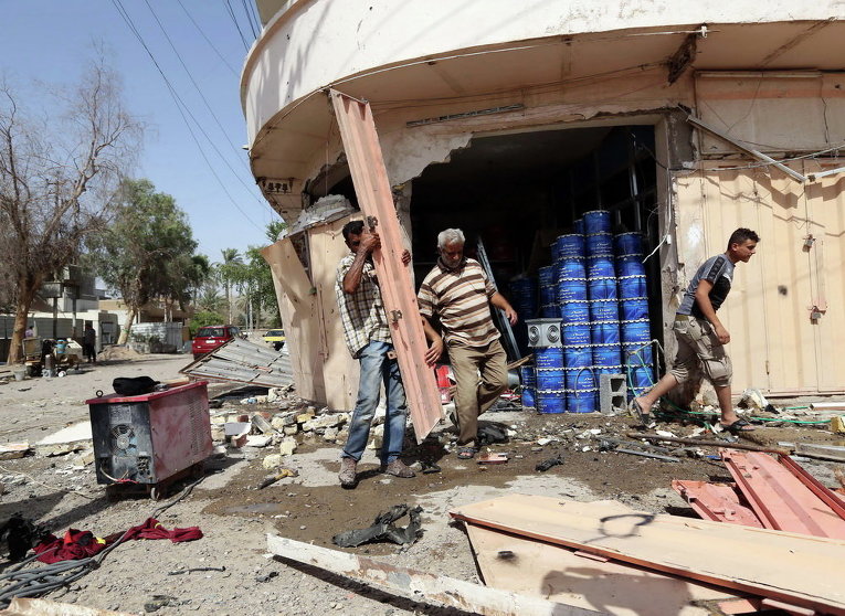 Гражданские осматривают место взрыва заминированного автомобиля в северном районе Багдада, Ирак