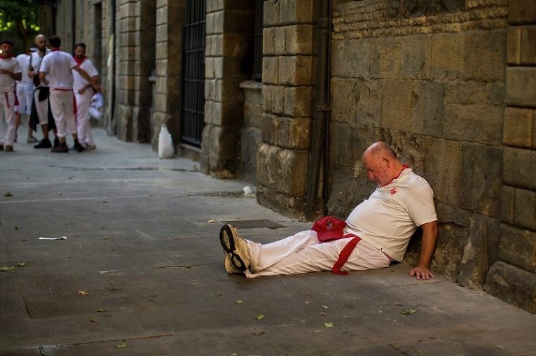 Мужчина спит после забега с быками во время фестиваля Сан-Фермин в Испании