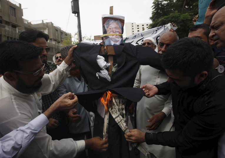 Трейдеры сжигают чучело министра финансов Пакистана Исхака Дара во время акции протеста против введения процента на доходы по по банковским операциям.