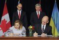 Премьер-министр Арсений Яценюк (на заднем плане слева) и премьер-министр Канады Стивен Харпер (на заднем плане справа) во время подписания Соглашения о свободной торговле между Украиной и Канадой в Оттаве