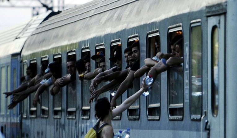 Мигранты просят воду в перегруженном поезде на железнодорожной станции Гевгелия в Македонии