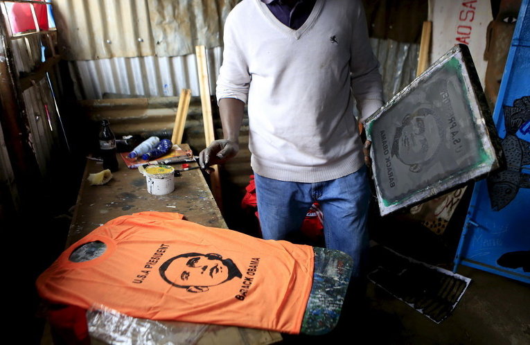 Мужчина наносит портрет президента США Барака Обамы на футболку в маленькой мастерской в трущобах Кибера накануне приезда Обамы в столицу Кении Найроби