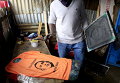 Мужчина наносит портрет президента США Барака Обамы на футболку в маленькой мастерской в трущобах Кибера накануне приезда Обамы в столицу Кении Найроби