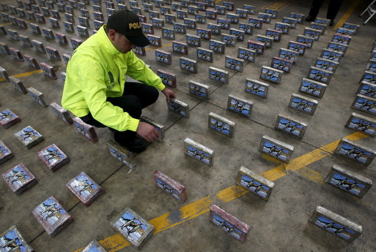 Колумбийский полицейский по борьбе с наркотиками проверяет пакеты кокаина на базе полиции в Боготе