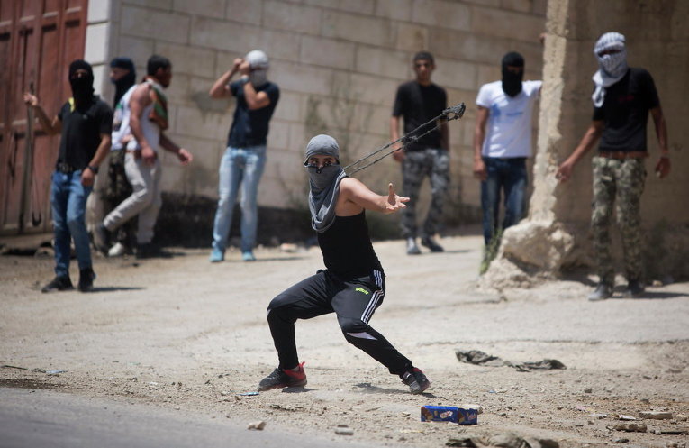 Палестинцы использует рогатки против израильских солдат во время столкновений после похорон Фалах Абу Марии в деревне Бейт-Омар на Западном берегу Хевроне