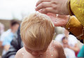 Ребенок во время массового крещения. Архивное фото