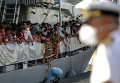 Мигранты ждут высадки с ирландского корабля ВМС LE Niamh в сицилийском порту Мессина