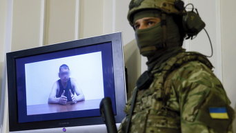 Офицер СБУ стоит рядом с монитором, на котором показан человек, являющийся, по данным СБУ, майором российской армии. Он был задержан украинскими спецслужбами на днях