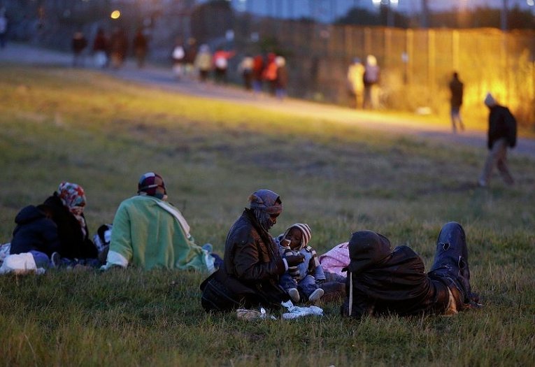 Незаконные мигранты кормят детей рядом с ограждением Евротоннеля, по которому они пробираются из Франции в Великобританию