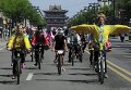 Мужчина в традиционном костюме китайского императора и другие участники акции ездят на велосипедах по улице в Датуне