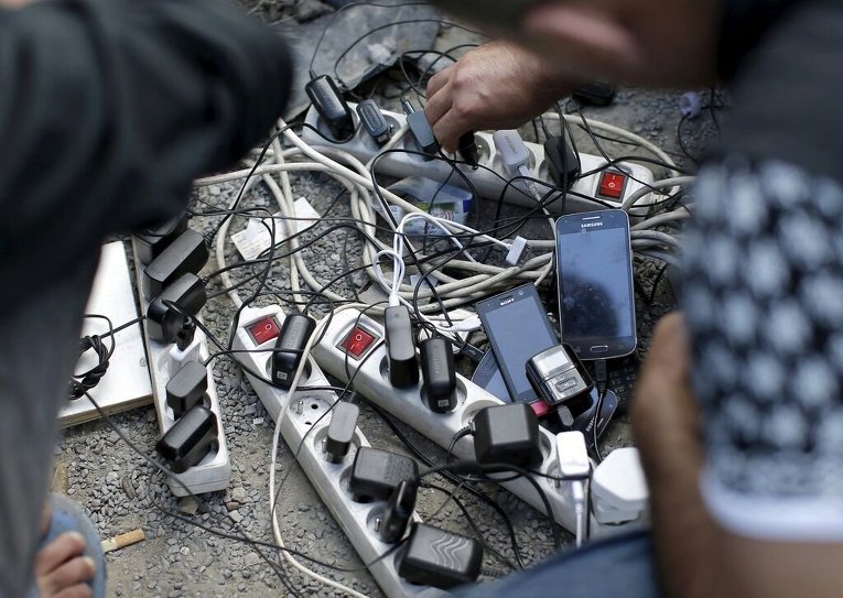 Мигранты из Афганистана заряжают мобильные телефоны в лагере в Кале, Франция