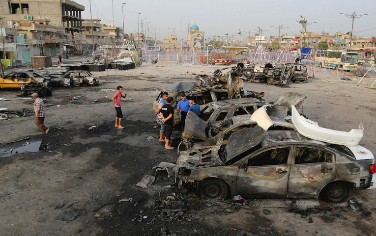 Люди осматривают место взрыва заминированного автомобиля в шиитском районе в Багдаде, Ирак