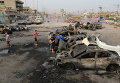 Люди осматривают место взрыва заминированного автомобиля в шиитском районе в Багдаде, Ирак