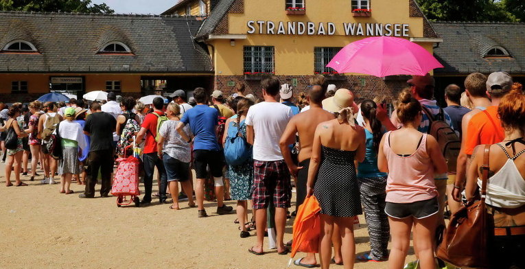Люди стоят в очереди у входа в Berlin's Wannsee lido в жаркий летний день, Германия