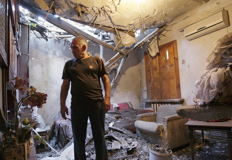 Человек стоит посреди развалин своего разрушенного обстрелом дома в Донецке