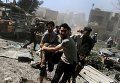 Мужчины несут раненого после авиаудара на оживленном рынке в Дамаске, Сирия