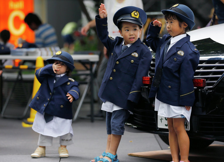 Дети в полицейских костюмах позируют в деловом районе Токио, Япония