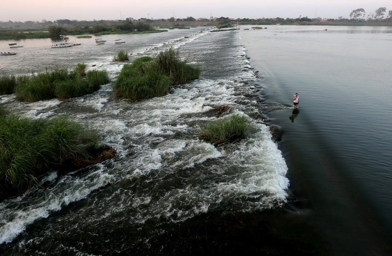 Мужчина спасается от жары в реке Нил на окраине Каира, Египет