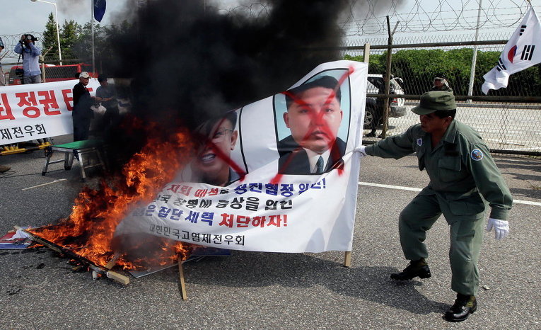 Протестующие жгут баннер с изображением лидера КНДР Ким Чен Ына и его покойного отца Ким Чен Ира во время митинга против Северной Кореи в Южной Корее