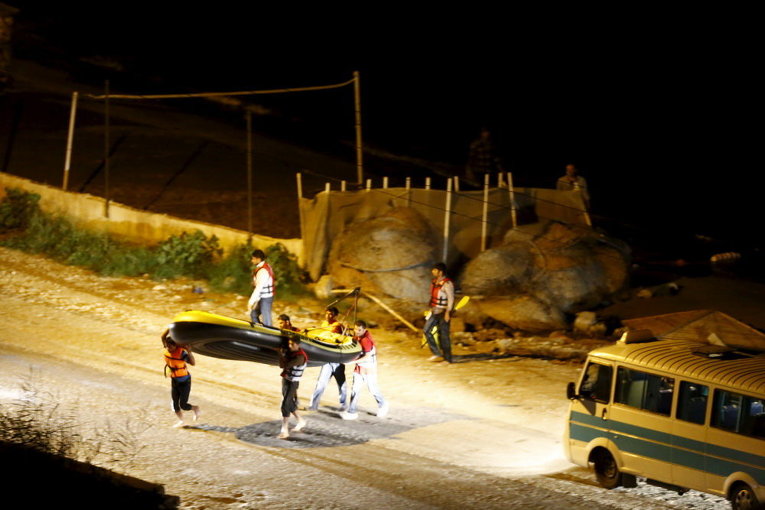 Мигранты несут лодку обратно на берег после того, как береговая охрана Турции прибыла на место происшествия в прибрежном городе Бодрум, Турция