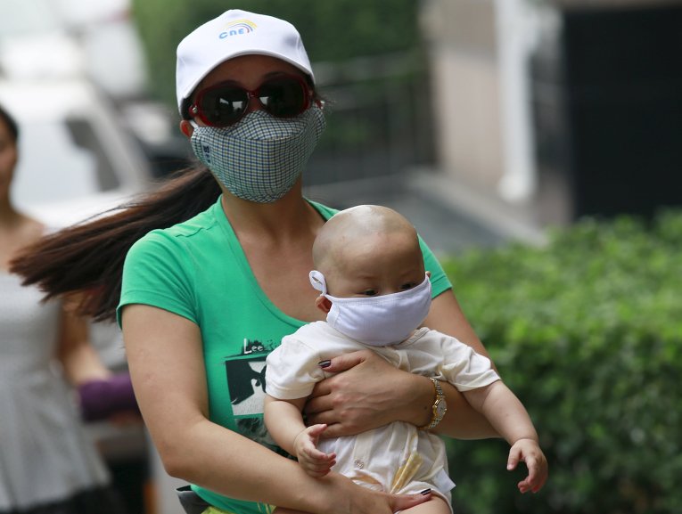 Женщина с ребенком идут по улице в пяти километра от места взрыв в Тьянцзыне, Китай