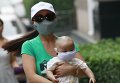 Женщина с ребенком идут по улице в пяти километра от места взрыв в Тьянцзыне, Китай