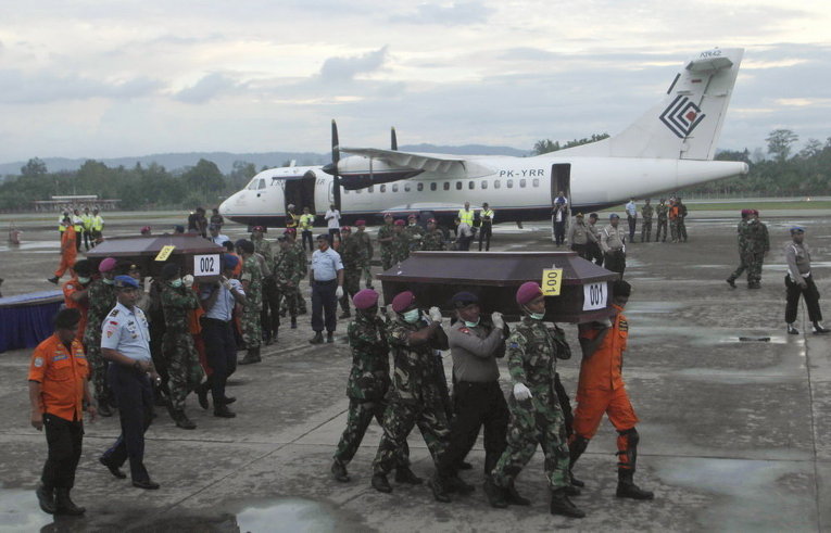 Индонезийские силы безопасности и спасатели несут гробы с останками пассажиров потерпевшего крушение самолета Air Trigana в  аэропорту, недалеко от Джаяпура, провинции Папуа, Индонезия