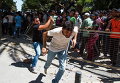 Греческий полицейский в штатском прогоняет пакистанского мигранта, который начал кричать во время ожидания на регистрацию возле полицейского участка в юго-восточной части острова Кос, Греция