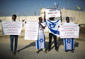 Демонстранты держат плакаты и флаги с призывом освободить Авраама Менгисто на КПП Эрез на юге Израиля, недалеко от сектора Газа